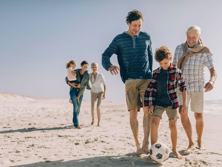Familienurlaub am Meer, Kinder, Eltern und Großeltern beim Strandspaziergang