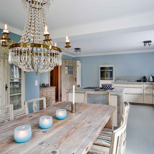 Kronleuchter über dem Esstisch im Ferienhaus Fährhüs Nobler Essbereich mit Kronleuchter und antikem Geschirrschrank